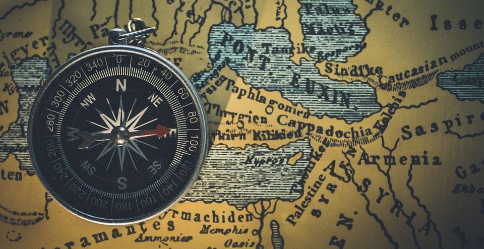 A brass compass resting on an old map