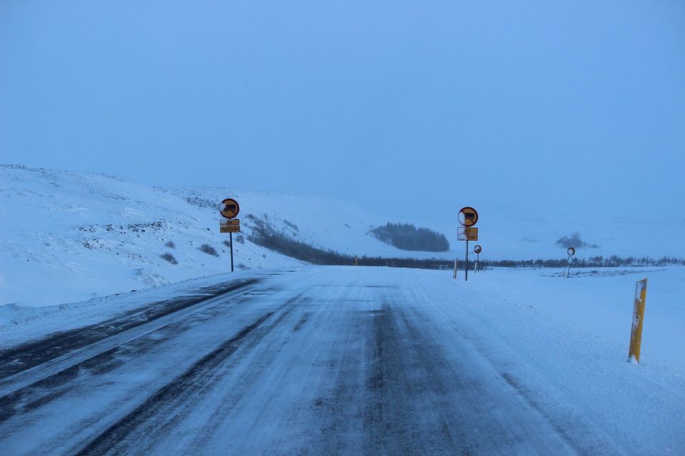 A snow-covered road in Iceland stretching into the white distance