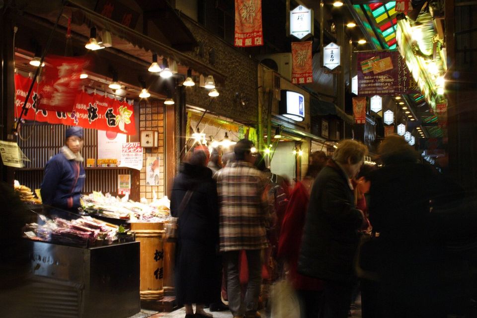 Shoppers walking through a covered market lit by lanterns