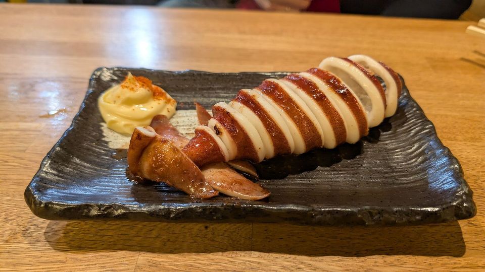Grilled squid stuffed with rice on a dark plate