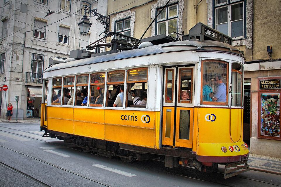 Yellow vintage tram climbing a narrow street in Lisbon