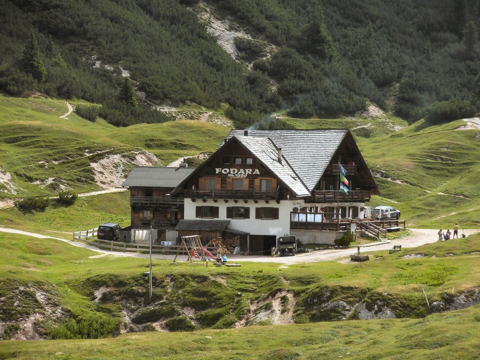 A mountain hut with wooden balconies on a green alpine meadow