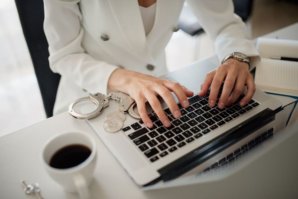 Hands typing on a laptop next to a cup of coffee